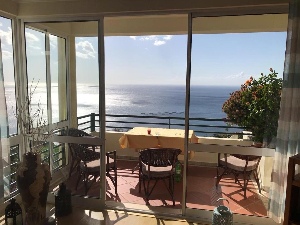 einen Balkon mit einem Tisch, Stühlen und Meerblick in der Unterkunft Apartamento do Sol in Arco da Calheta