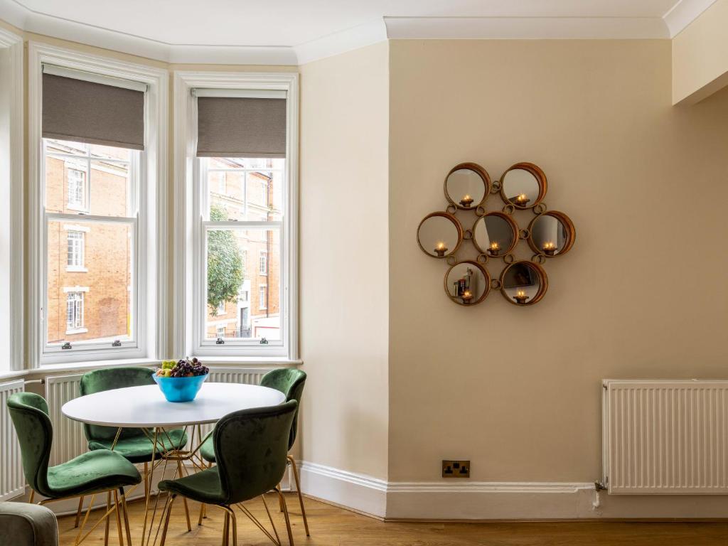 One Bedroom Apartment in Marylebone في لندن: غرفة طعام مع طاولة وكراسي ونوافذ