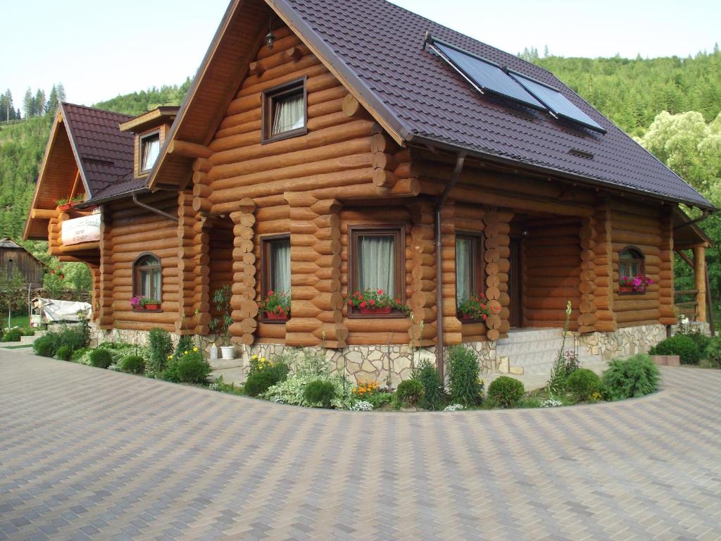 a log cabin with a solar roof on a driveway at Cabana Piatra Runcului in Vatra Moldoviţei