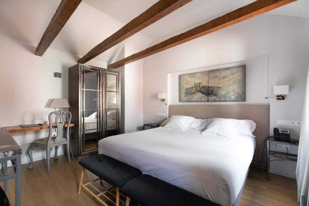 a bedroom with a large white bed and a desk at Hospedium Hotel Posada de la Silleria in Toledo