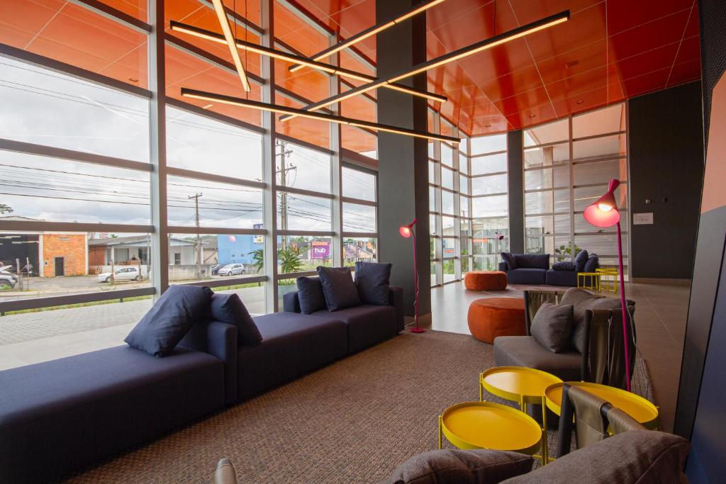 a living room with a couch and chairs and windows at Hotel Darolt Criciúma in Criciúma