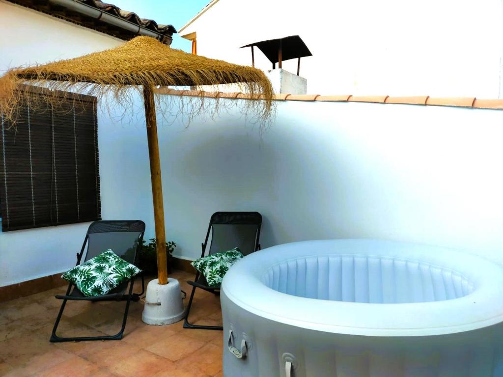 a hot tub with two chairs and an umbrella at APARTAMENTOS FERNANDO III EL SANTO in Baeza