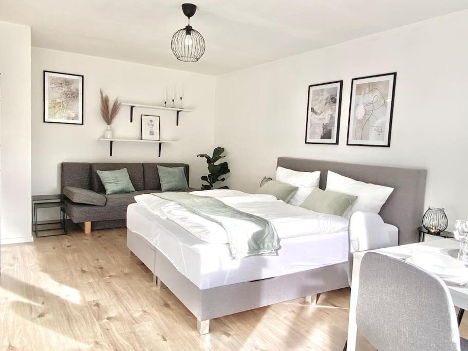 - une chambre blanche avec un grand lit et un canapé dans l'établissement Top-Apartment mit Parkplatz und Balkon, à Reutlingen
