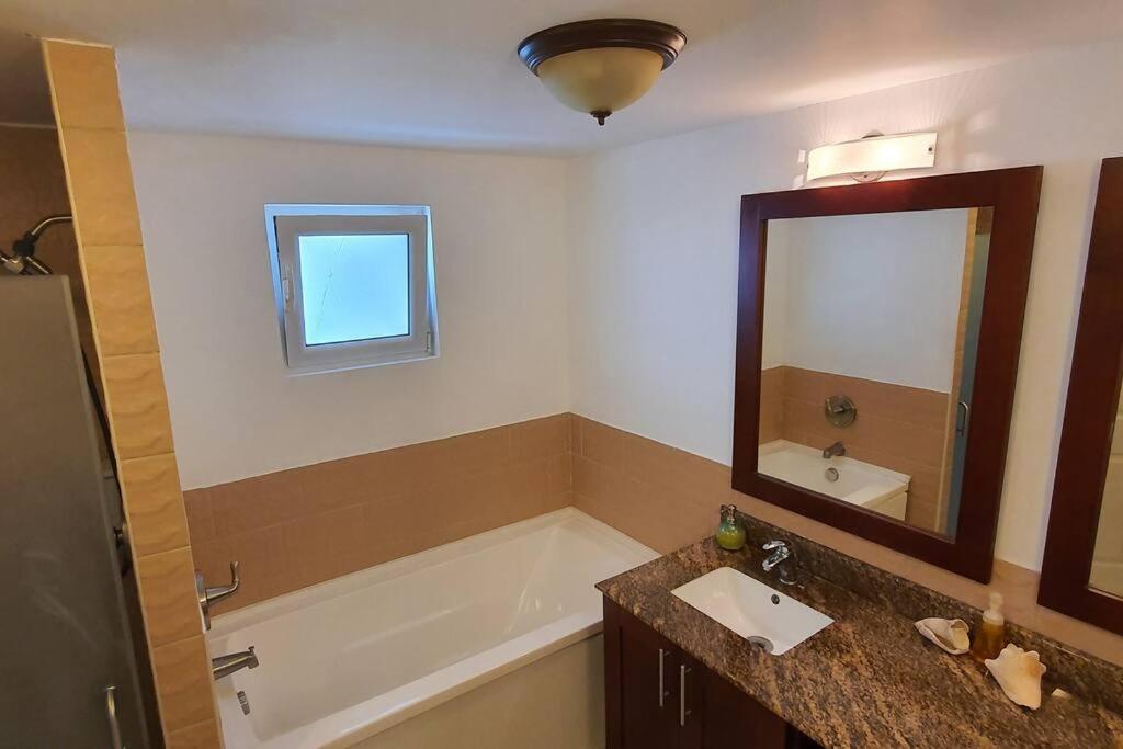 y baño con bañera, lavabo y espejo. en Sunset Beach View - Luxury Studio next to The Morgan Resort en Maho Reef