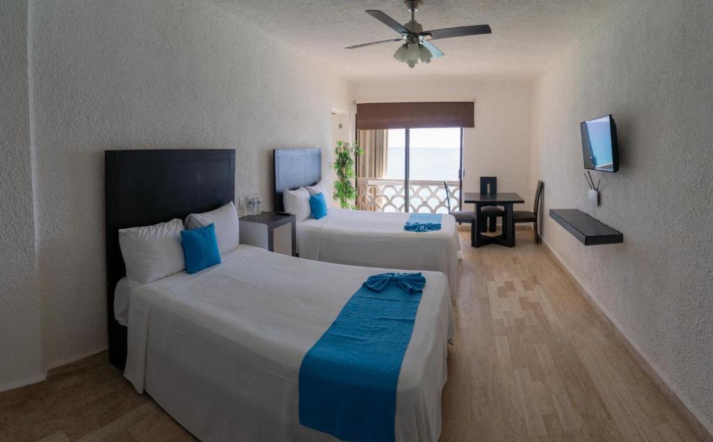 a hotel room with two beds and a television at Cancún Plaza Sea View in Cancún