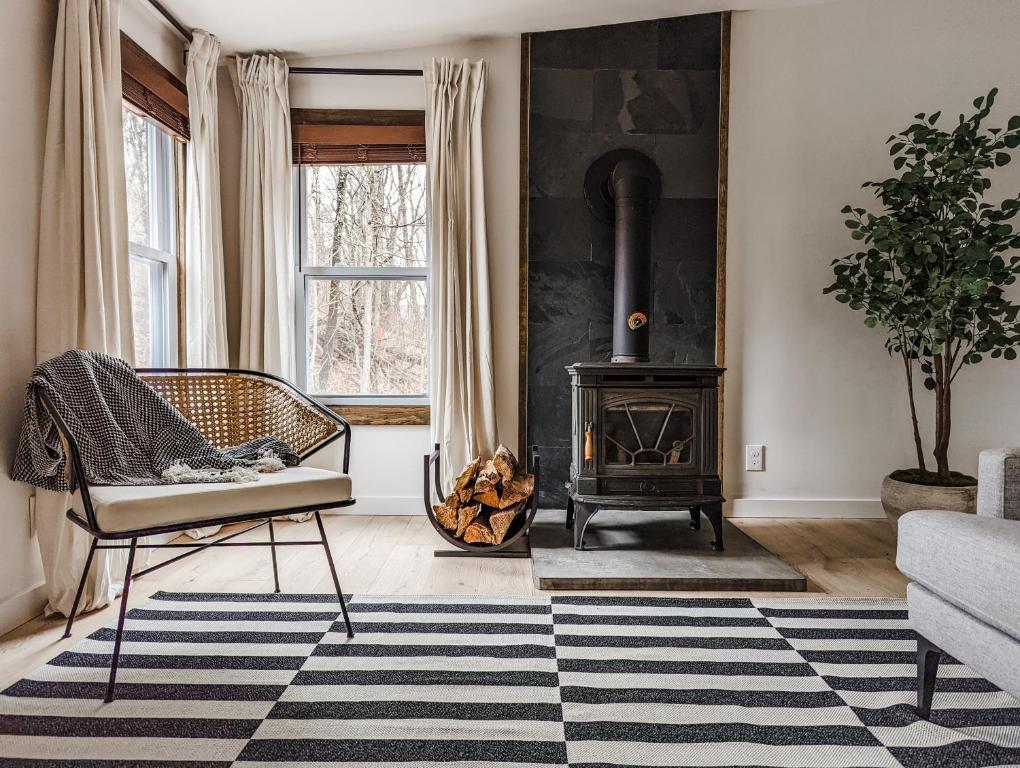- un salon avec une cheminée, une chaise et une cuisinière dans l'établissement Pinewood Bungalow - Luxury Cabin, Kid-Friendly, à Catskill