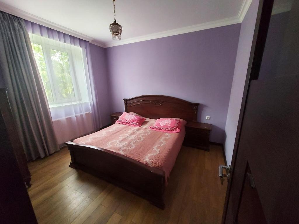 a bedroom with purple walls and a bed with two pink pillows at Гостевой дом в центре Тбилиси in Tbilisi City