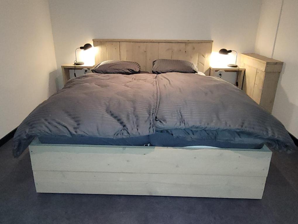 uma cama num quarto com duas lâmpadas em duas mesas em Timmershoeve em Vorstenbosch