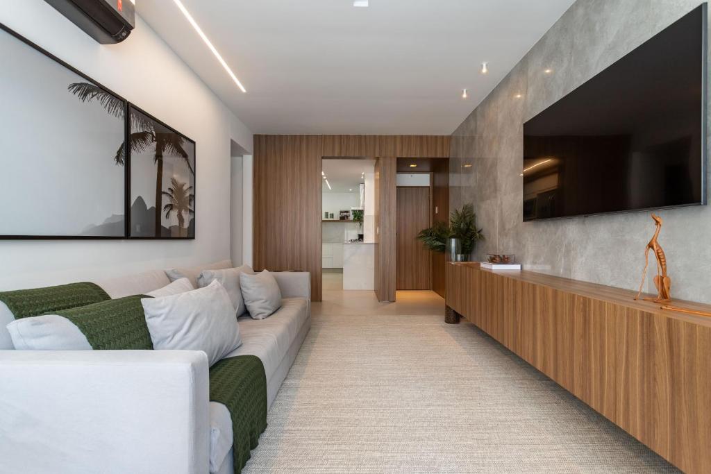 uma sala de estar com um sofá e uma televisão de ecrã plano em Agradável em Ipanema - 2 suites completas - J303 Z2 no Rio de Janeiro