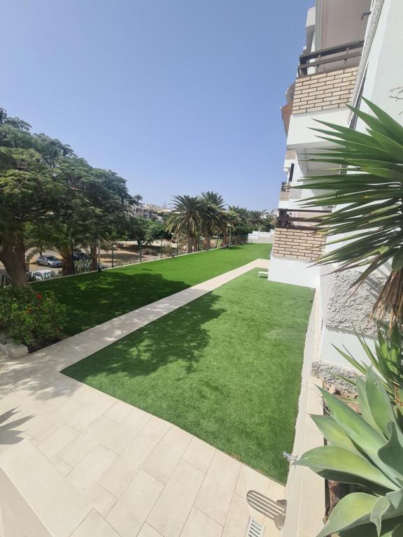 einen Hof mit grünem Gras und einem Gebäude in der Unterkunft Endless Summer in San Bartolomé de Tirajana