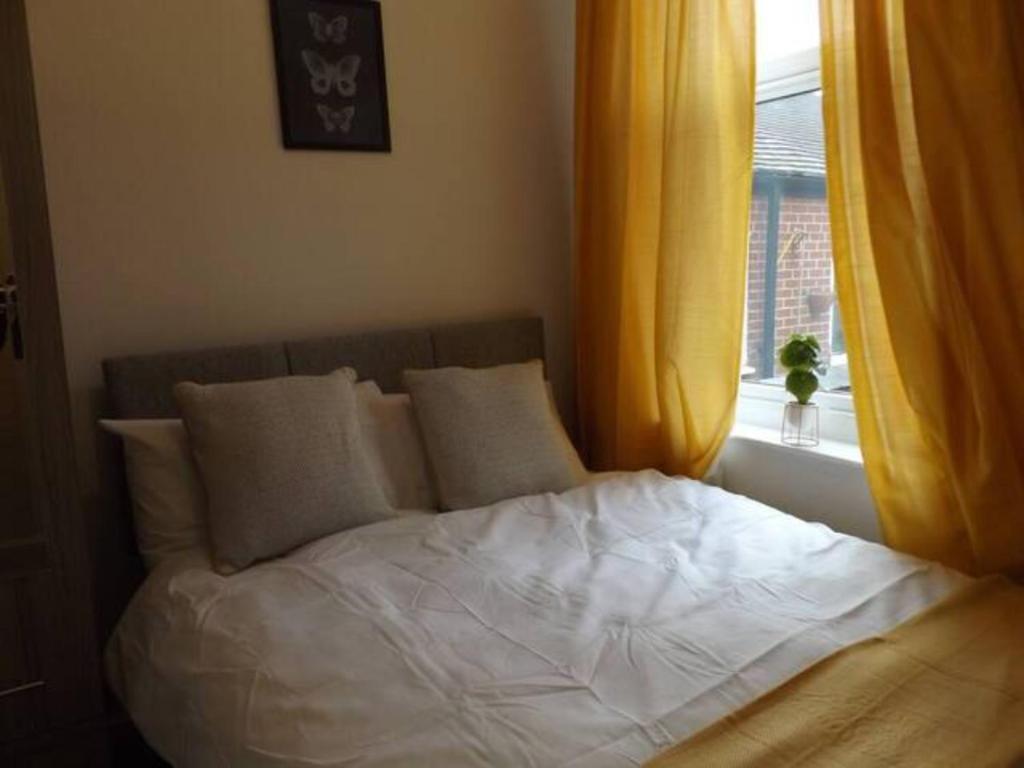 a bed with white sheets and pillows in front of a window at Forest Park House in Hanley