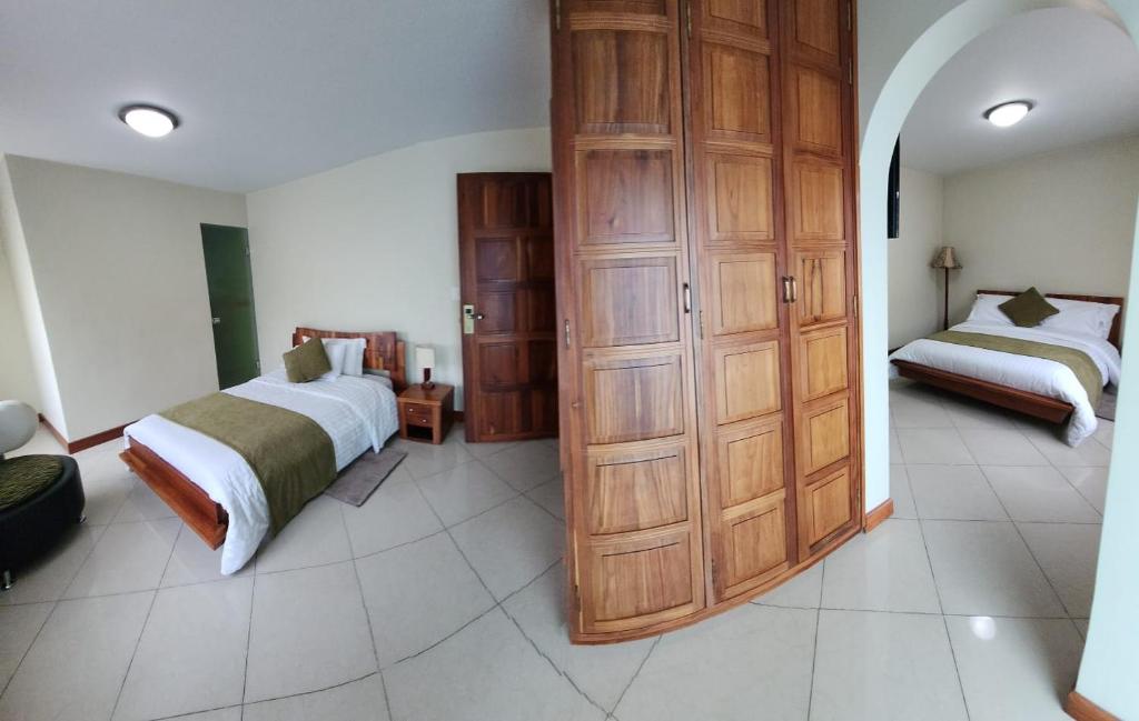 1 dormitorio con 1 cama y un gran armario de madera en Apartahotel Vincent Suites, en Pasto