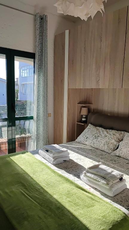 - une chambre avec un lit doté de draps verts et une fenêtre dans l'établissement A pochi passi dal mare, à Torvaianica