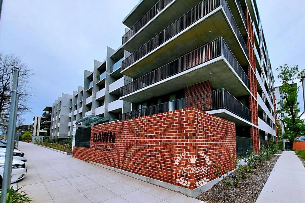 um edifício alto de tijolos vermelhos numa rua em Modern new 1-bedroom apartment in Canberra City em Camberra