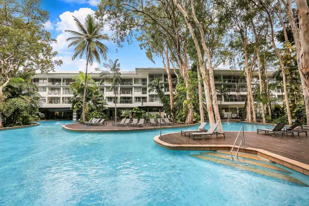 um resort com uma piscina com cadeiras e palmeiras em Hotel Drift 4202 em Palm Cove