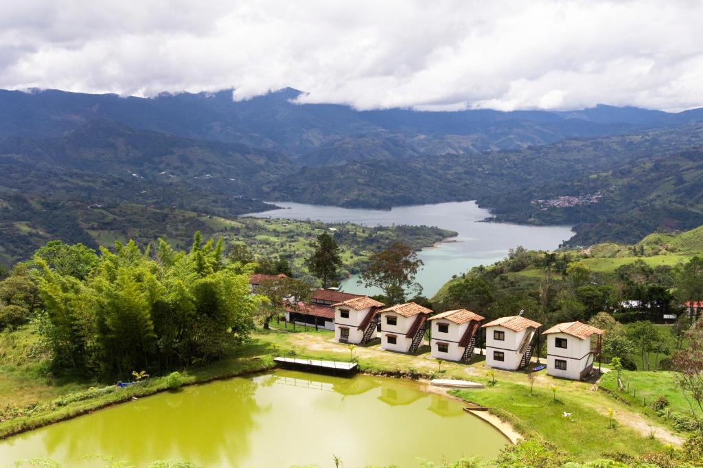 a group of houses on a hill next to a lake at Hotel Campestre Entre Cerros in Ubalá