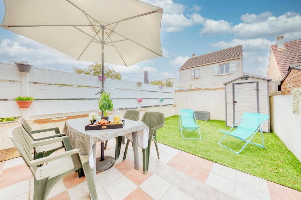 une terrasse avec une table, des chaises et un parasol dans l'établissement appartement tout équipé avec terrasse et parking privé, à Brétigny-sur-Orge