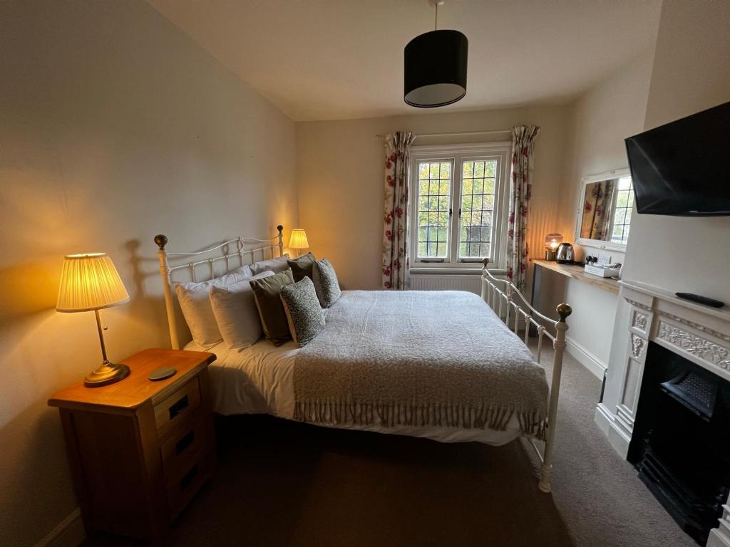 a bedroom with a bed and a table with a lamp at White Hart in Alton