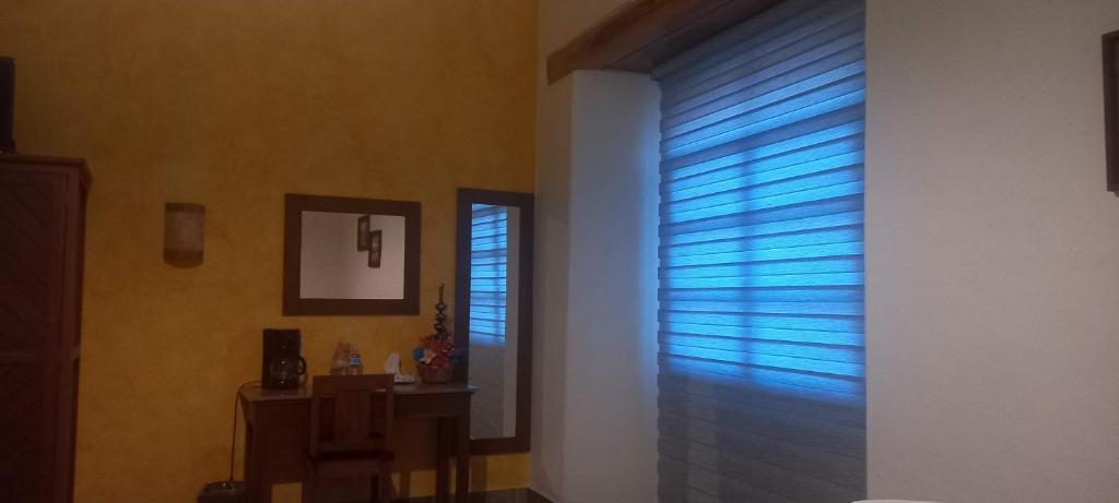 a hallway with a window with blue blinds at Casa Esmeralda Hotel in Oaxaca City