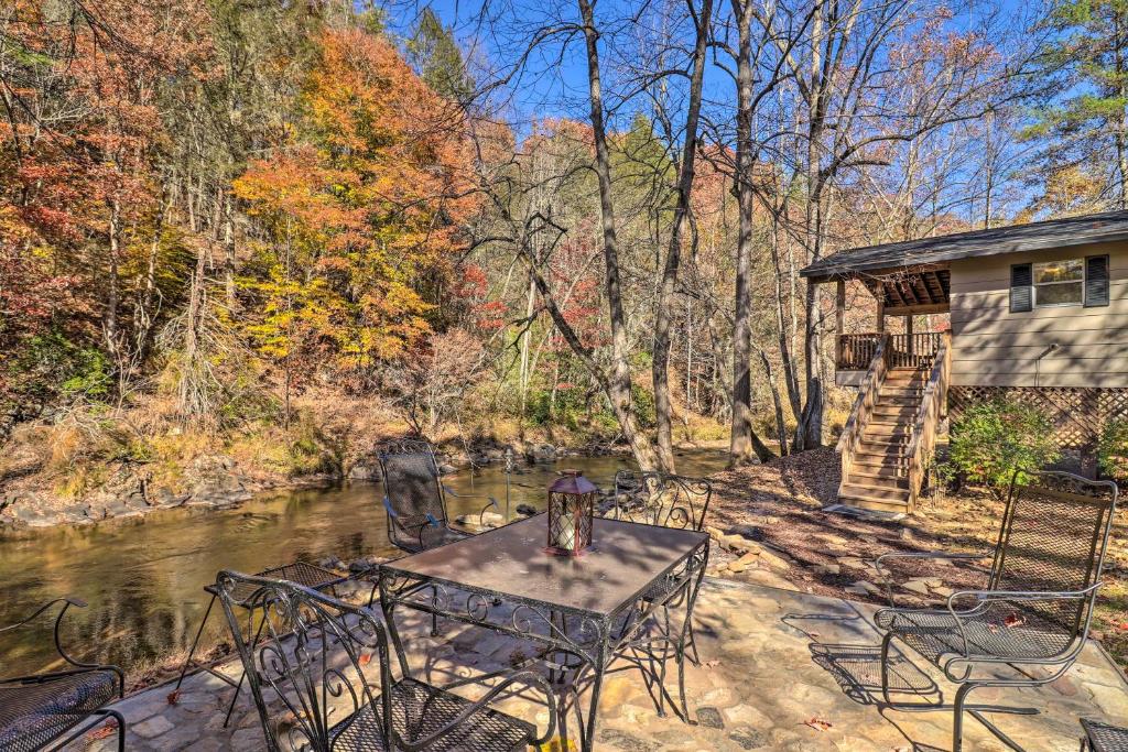 a table and chairs on a patio next to a river at Creekside Retreat with Deck, 18 Miles to Wolf Ridge in Weaverville