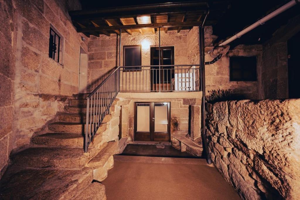 un edificio in pietra con scale e balcone di Casa Rural Vilar de Flores a Ourense