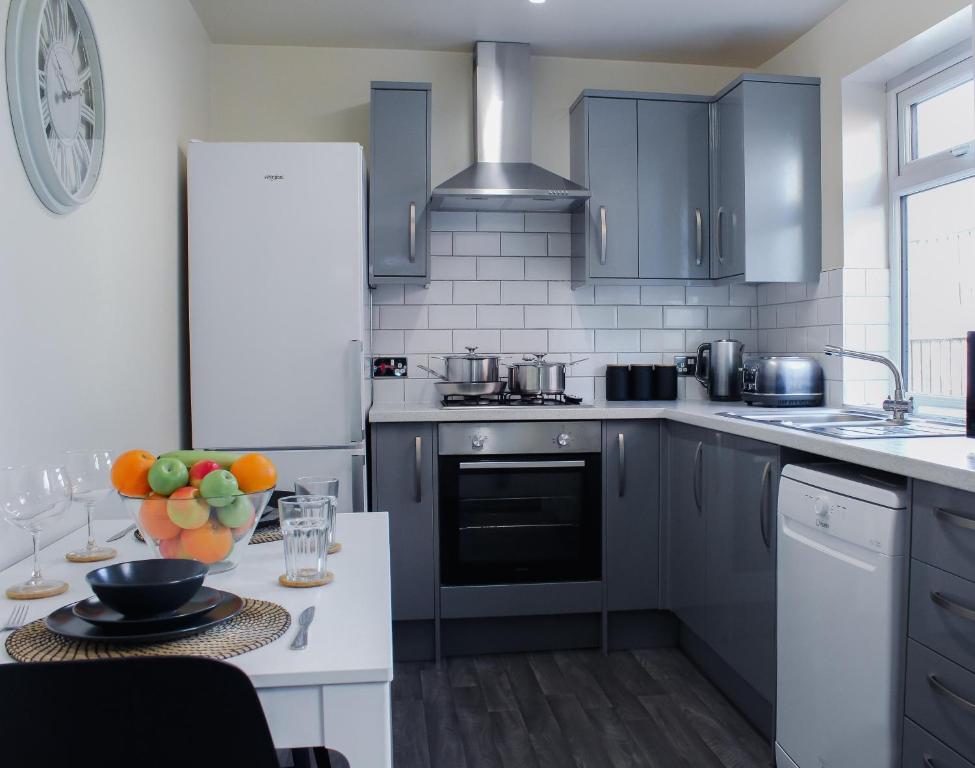 uma cozinha com armários azuis e uma mesa com uma taça de fruta em Victoria Cottage em Cannock