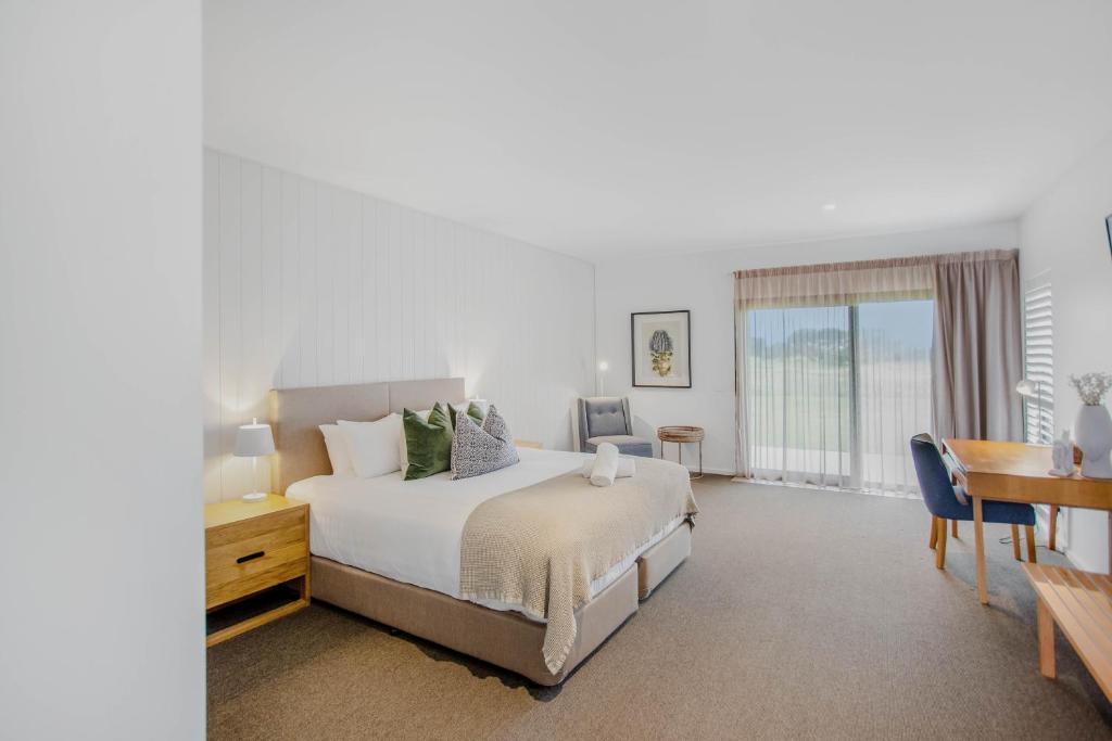 a bedroom with a bed and a table and a desk at 13th Beach Golf Lodges in Barwon Heads