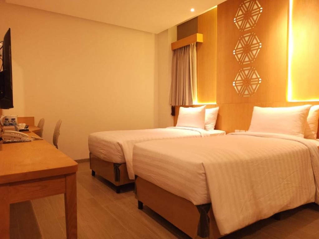 una camera d'albergo con due letti e una scrivania di UNUMA HOTEL a Giacarta