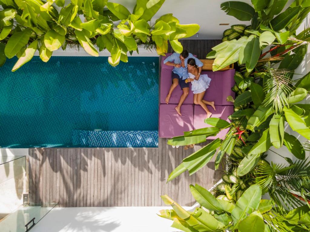 a family sitting on the edge of a swimming pool at Eight Palms Villa Seminyak by Ini Vie Hospitality in Seminyak
