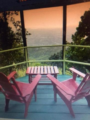 2 rosa Stühle und ein Picknicktisch auf einer Veranda in der Unterkunft Ginger Lodge Cottage, Peters Rock, Woodford PO St Andrew, Jamaica - this property is not in Jacks Hill in Jacks Hill