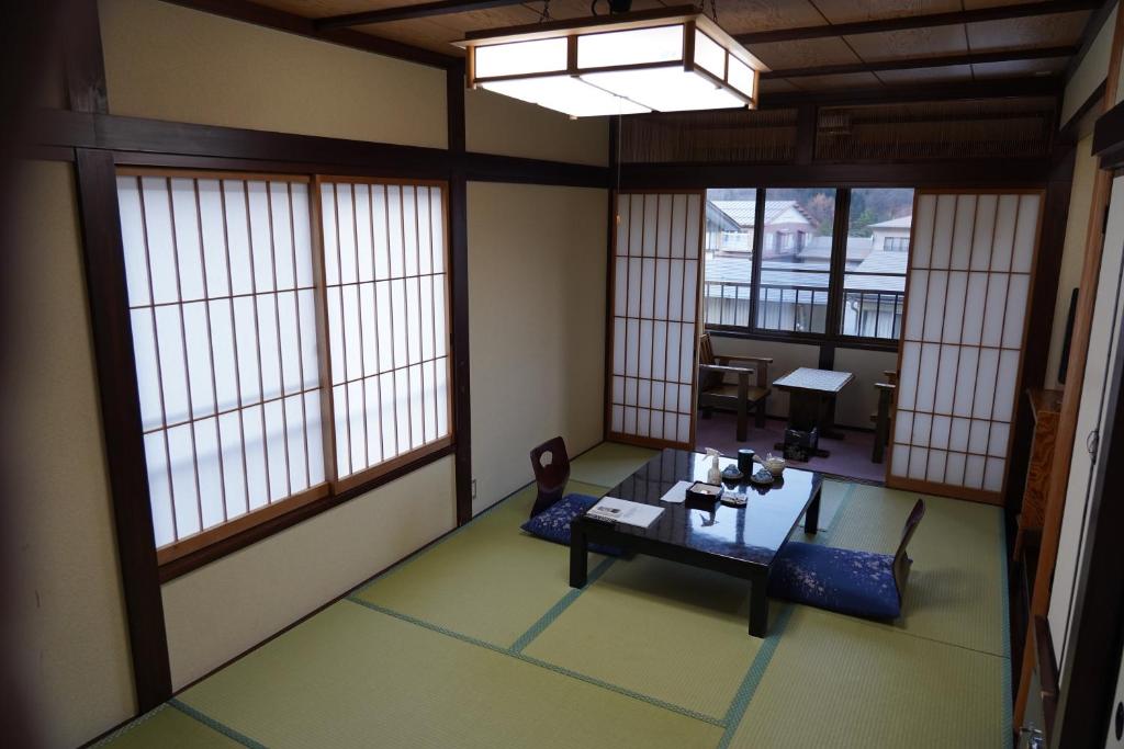 Zimmer mit Fenstern, einem Tisch und Stühlen in der Unterkunft Oyado Eitaro in Takayama