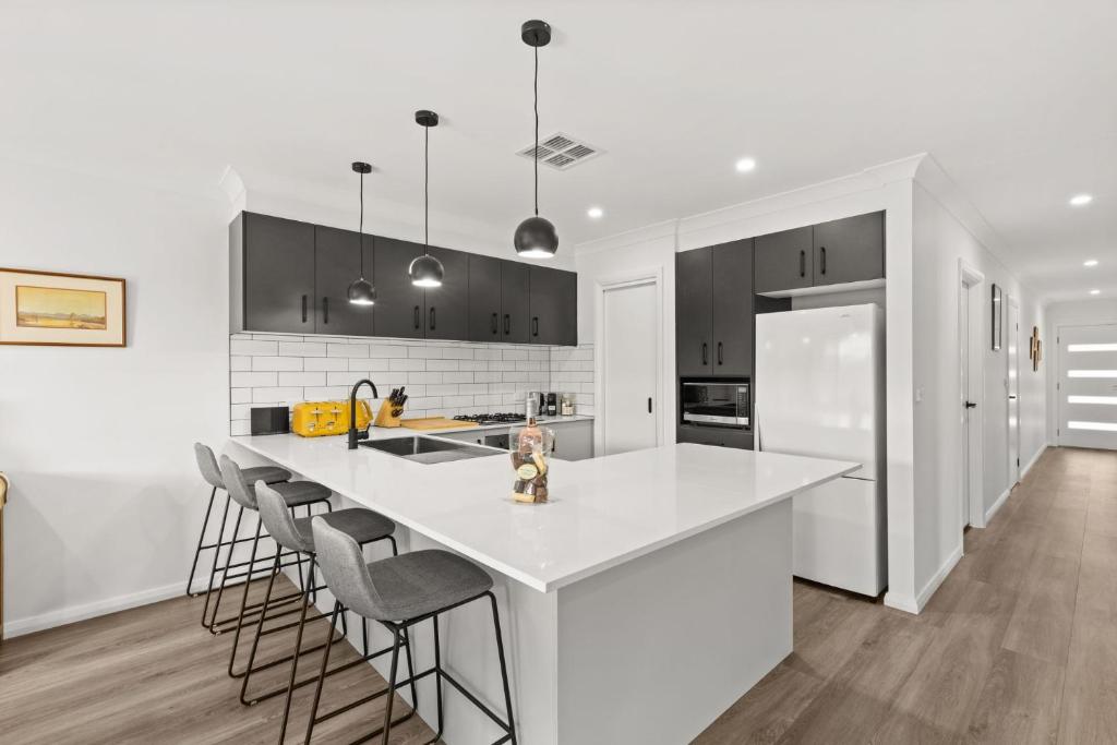 a white kitchen with a white counter top and black cabinets at Libbity's at The Point by Experience Jervis Bay in Sanctuary Point