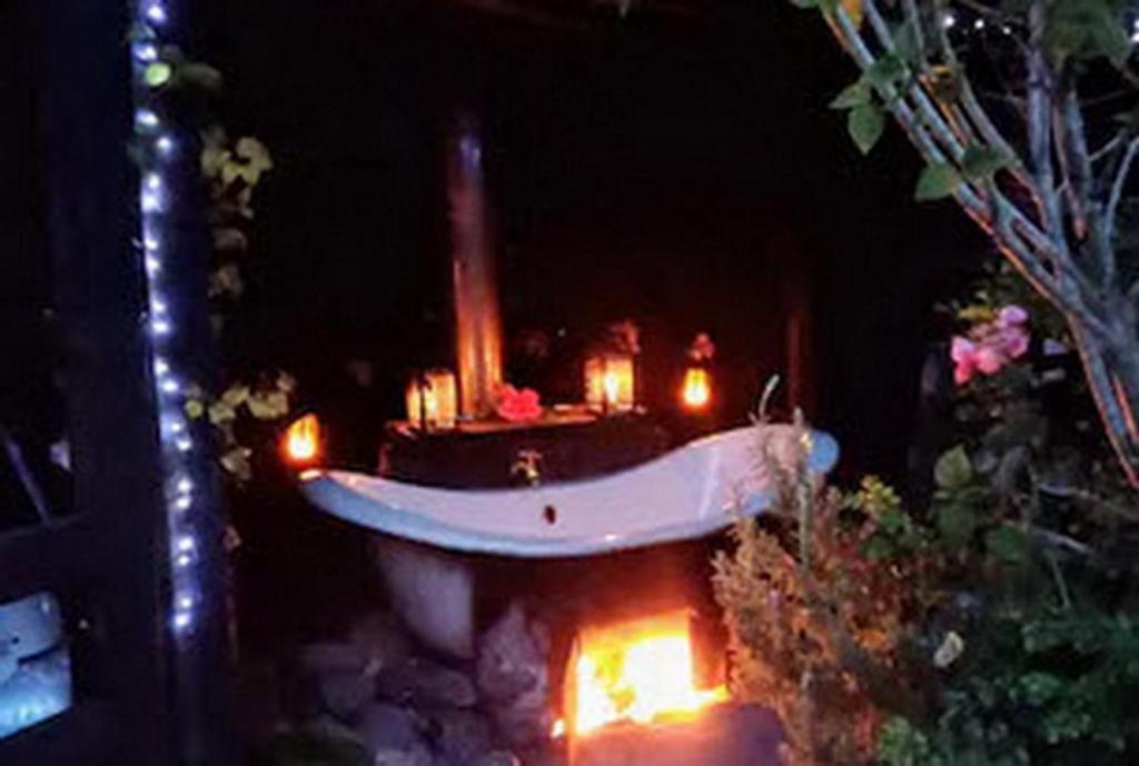 Warm Earth Cottages في Aongatete: وجود حوض استحمام بالشموع في الحديقة ليلا