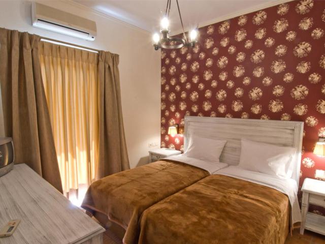 a bedroom with a large bed and a red wall at Fotis Rooms in Skafidia