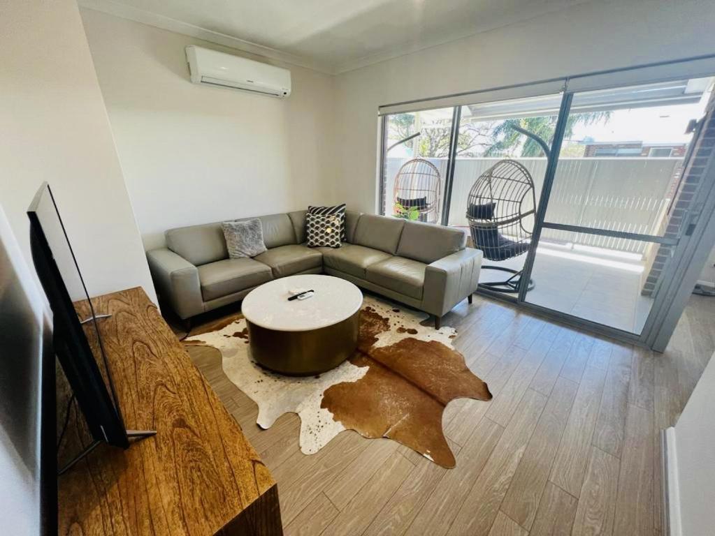 a living room with a couch and a table at Tranquil Tree Views 2 Bedroom 2 Bathroom Apartment in Perth