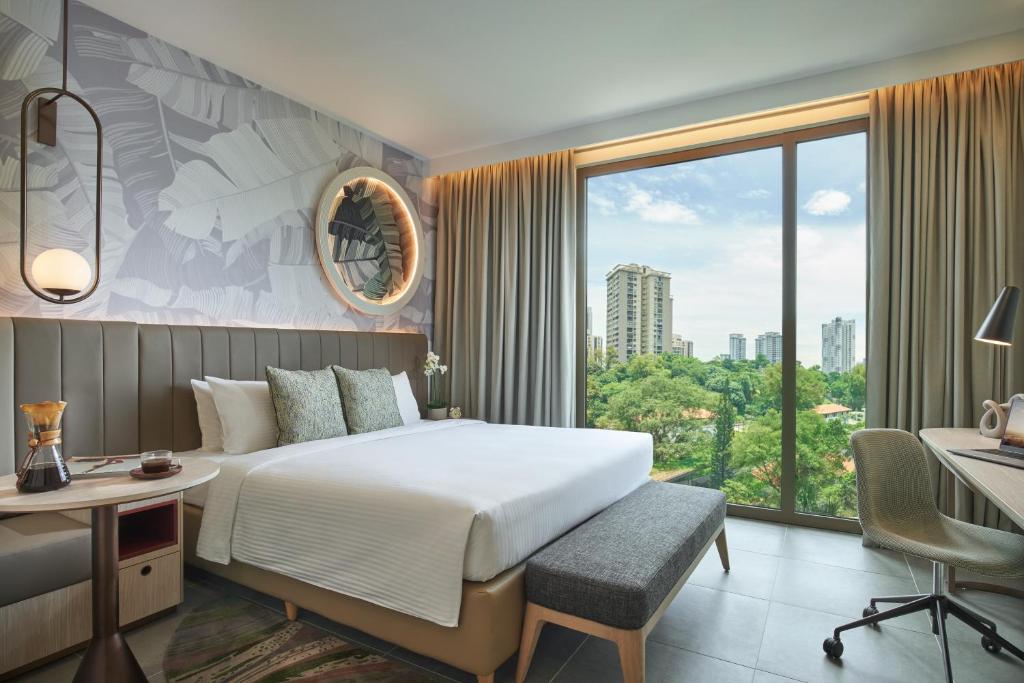 a hotel room with a bed and a desk and a window at Citadines Connect Rochester Singapore in Singapore