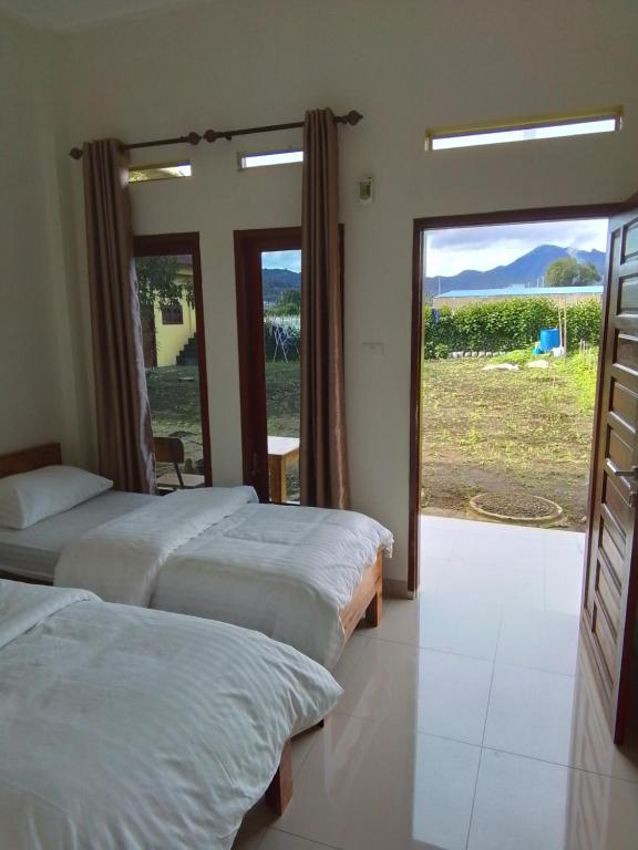 a bedroom with two beds and a sliding glass door at Berastagi Mountain View Homestay & Pizzeria in Berastagi