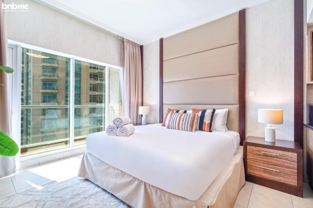 a bedroom with a large white bed and a window at bnbmehomes - Spacious Studio in Downtown Near Burj Khalifa - 1703 in Dubai
