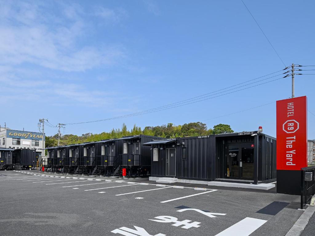 a row of black shipping containers in a parking lot at HOTEL R9 The Yard Shikokuchuo in Shikokuchuo