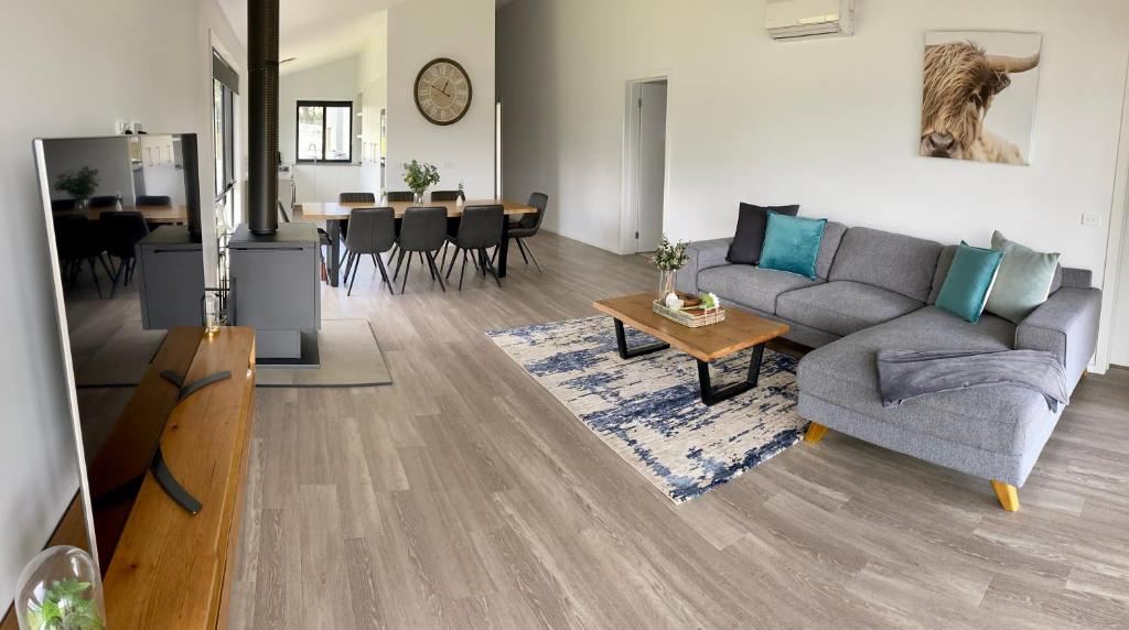 uma sala de estar com um sofá e uma mesa em Jindabyne House 1, Modern 3 bedroom home, alpine views & fireplace em Jindabyne