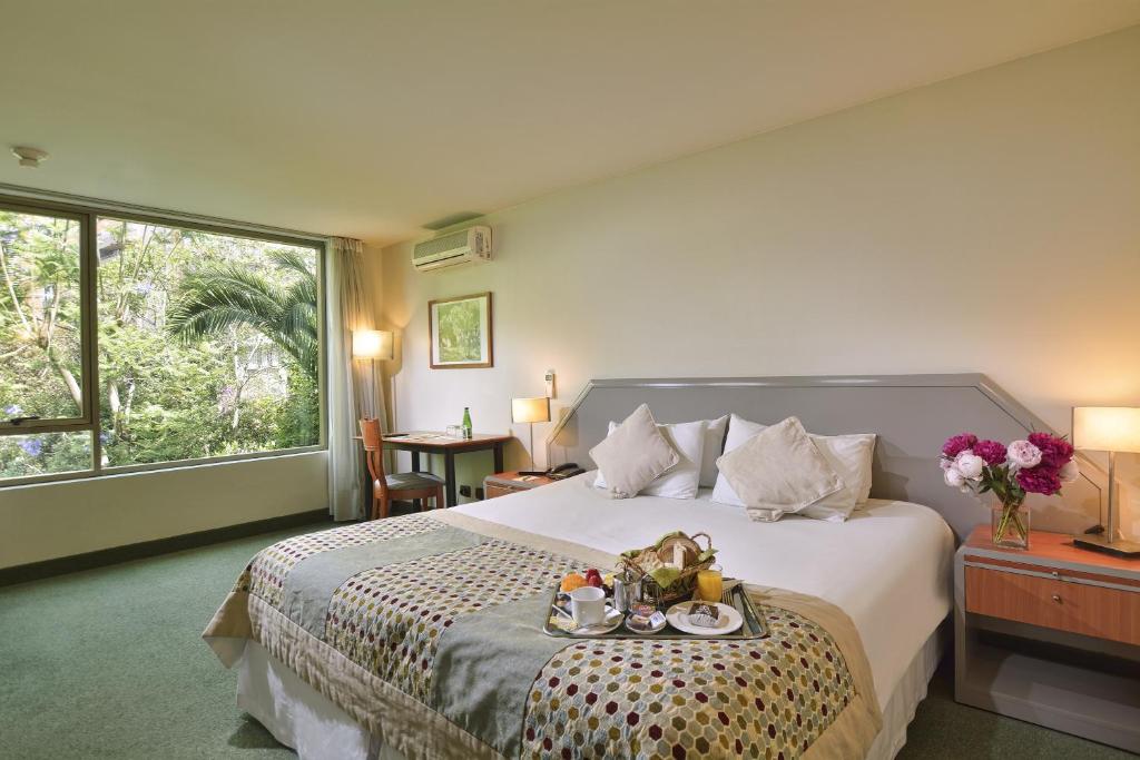 Un dormitorio con una cama con una bandeja de comida. en Hotel Eurotel El Bosque, en Santiago