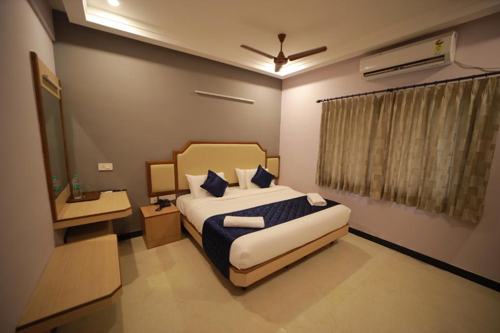 a bedroom with a king sized bed and a window at Majestic Hotel in Madurai