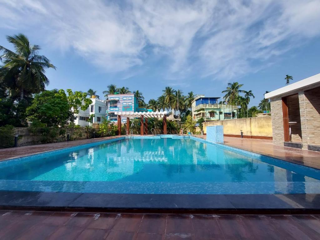 a large blue swimming pool with buildings in the background at ICONIC Hotel Digha in Digha