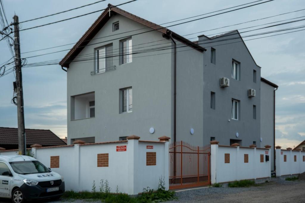 ein weißes Haus mit einem davor geparkt in der Unterkunft Solomon Apartments Room nr 5 in Sîngeorgiu de Mureş