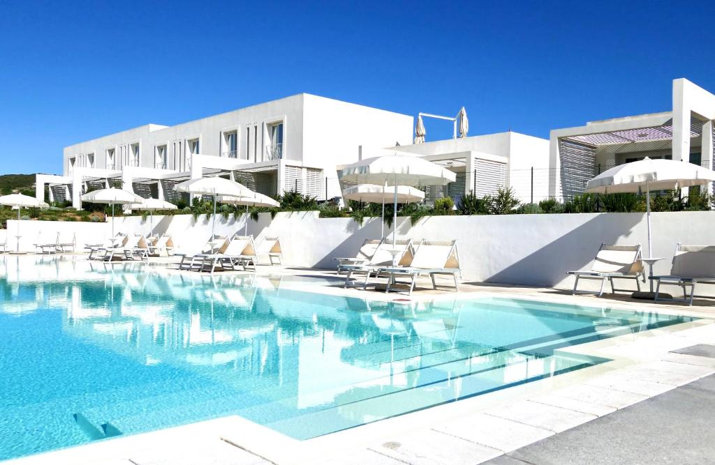 una piscina con sillas y sombrillas frente a un edificio en Resort con piscina a soli 250 mt dalla spiaggia La Pelosa, en Stintino