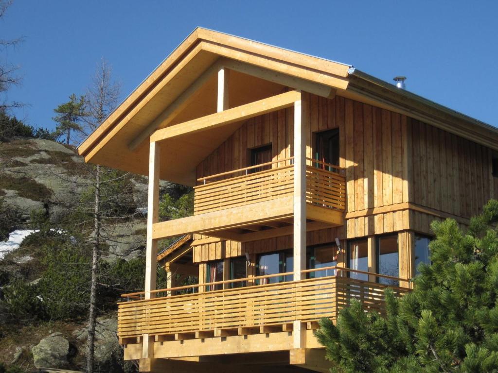 a large wooden house on a hill with trees at Chalet Alpenpark Turracherhöhe 4 in Turracher Hohe