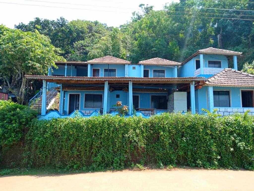 une maison bleue derrière une haie dans l'établissement Poornima Beach Stay, à Gokarna