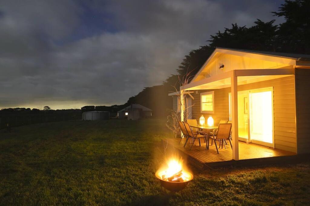 Cabaña pequeña con mesa y sillas en un campo por la noche en Cosy 3 bedroom cottage with indoor fireplace, en Romsey