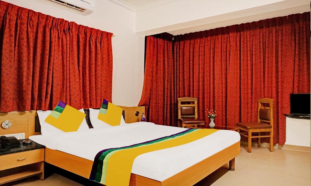 a bedroom with a large bed and red curtains at Itsy By Treebo - Crown Inn in Pune