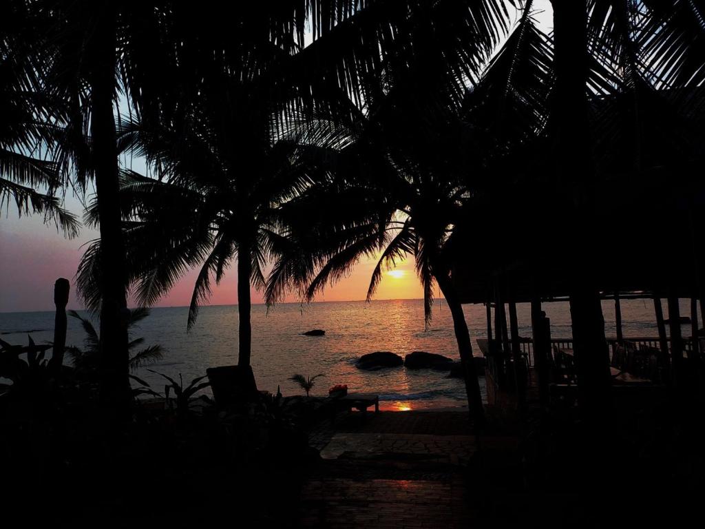 zachód słońca z plaży z palmami i oceanem w obiekcie Viet Thanh Resort w Duong Dong